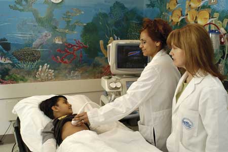 Photo of a pediatric radiologist scanning a boy's abdomen using ultrasound.