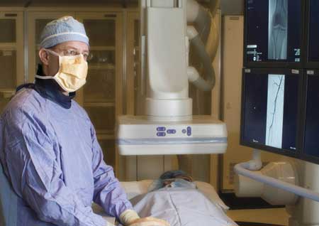 Interventional radiologist performing an angiography exam of a patient's leg vessels.