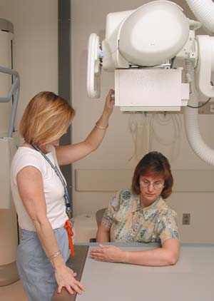 Tecnólogo radiólogo preparándose para realizarle rayos X al brazo de un paciente.