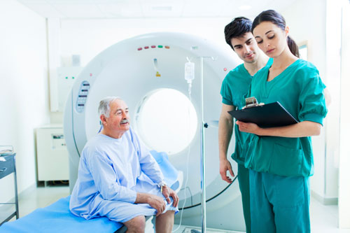 Photo of radiologic technologists reviewing a medical chart before performing a computed tomography (CT) scan.