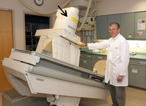 Image of a fluoroscopic table slightly tilted with an image intensifier (the 'x-ray eye') denoted by the arrow.