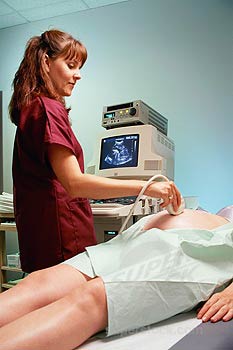 Technologist with patient undergoing obstetric ultrasound