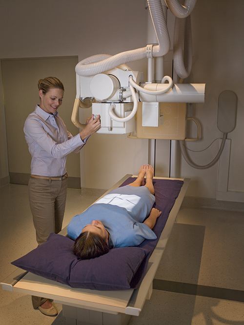 Radiólogo preparando a un paciente para una radiografía abdominal.
