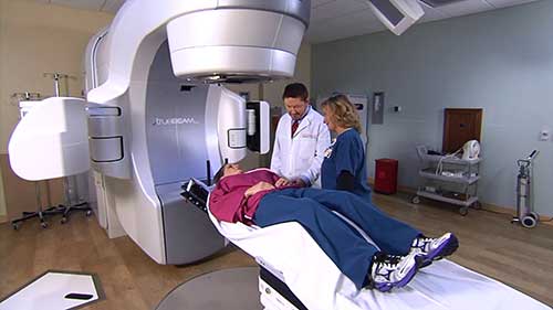 Radiologist and radiologic technologist prepping patient for radiation therapy treatment.