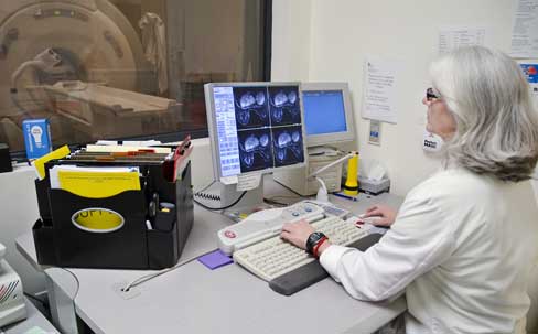 Photograph of a radiologist in a control room viewing breast MRI scans
