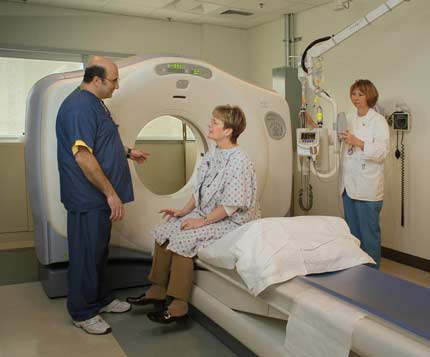 Photo of a technologist explaining an upcoming CT exam to a patient.