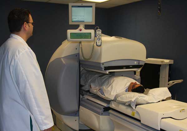 Photograph of a technologist performing a renal scan on a patient using a gamma camera.